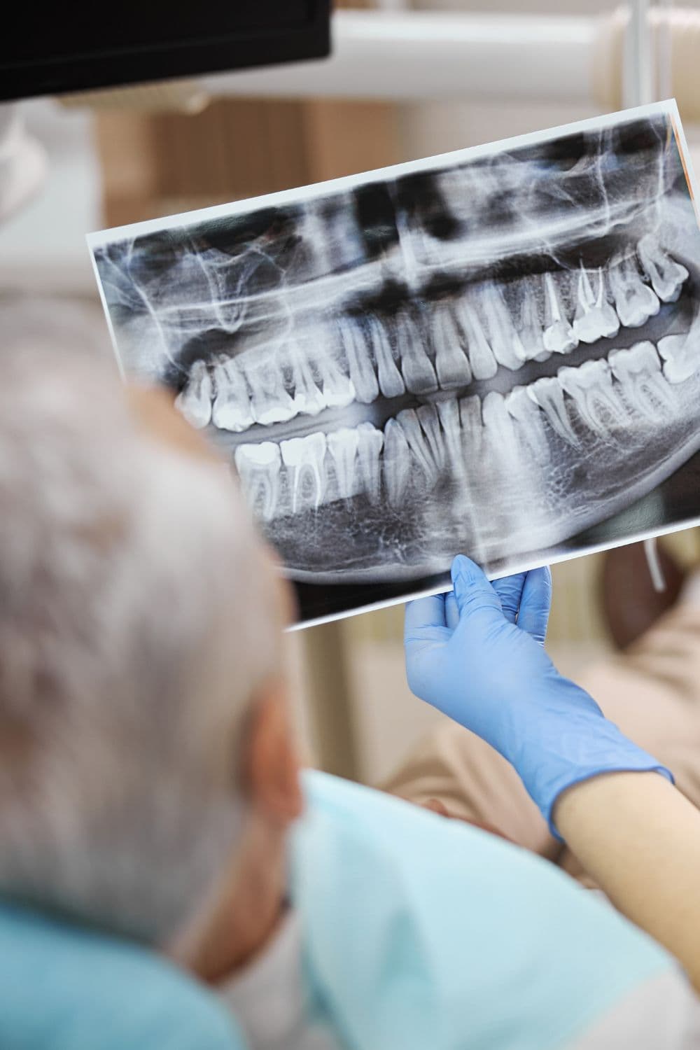 Paciente observando radiografia panorâmica com dentista durante planejamento de reabilitação oral